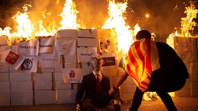 Independentistas quemando un muñeco que representa a Felipe VI este viernes por la noche en las calles de Barcelona.
