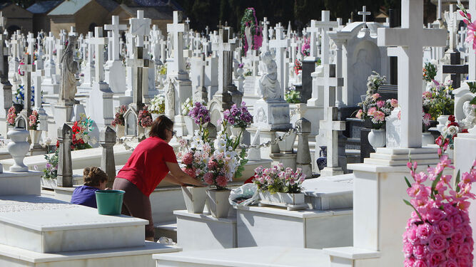 Imagen de archivo de dos mujeres adornando con flores una tumba en el cementerio de Sevilla.
