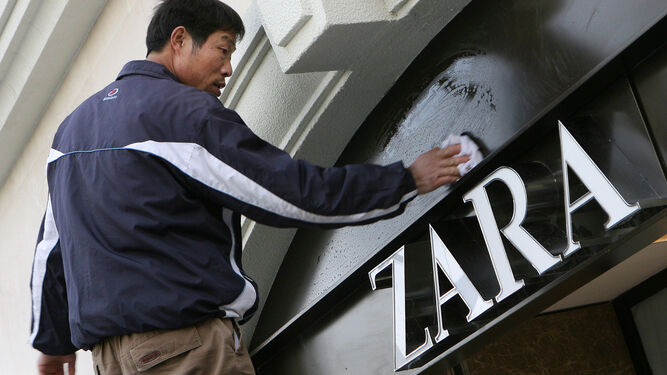 Un trabajador limpia el cartel de Zara en una tienda de Shanghai.
