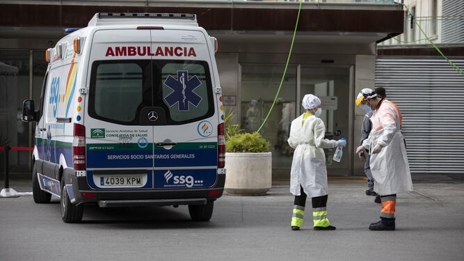 Dos técnicos de ambulancia desinfectan sus EPI en la puerta de Urgencias del Virgen de las Nieves