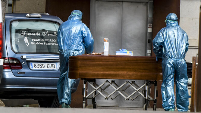 Trabajadores de una funeraria equipados con un EPI sacan un féretro de un hospital de Granada la pasada primavera