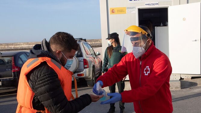 Un miembro de Cruz Roja atiende a uno de los inmigrantes rescatados a su llegada al Puerto de Motril.