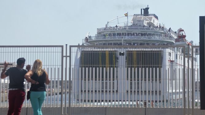 Dos personas observan la salidad de un ferry lleno de gente durante la Operación Paso del Estrecho de 2019