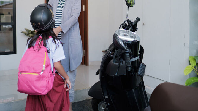 Una niña, preparada para ir al colegio en moto