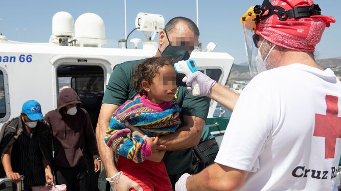 Un agente de la Guardia Civil coge a un menor inmigrante trasladado al Puerto de Motril durante este mes de septiembre.