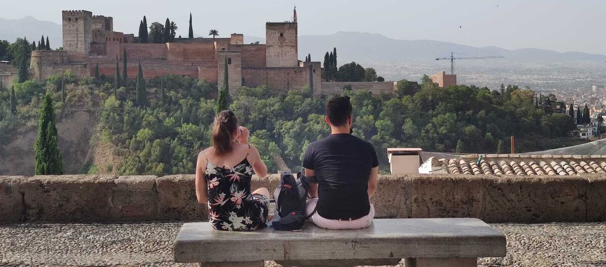 Dos jóvenes observan la Alhambra desde el mejor banco del mundo.