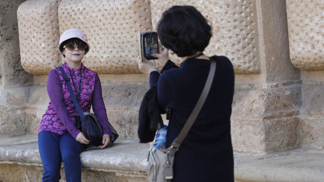 Dos asiáticas se fotografían junto al Palacio de Carlos V.