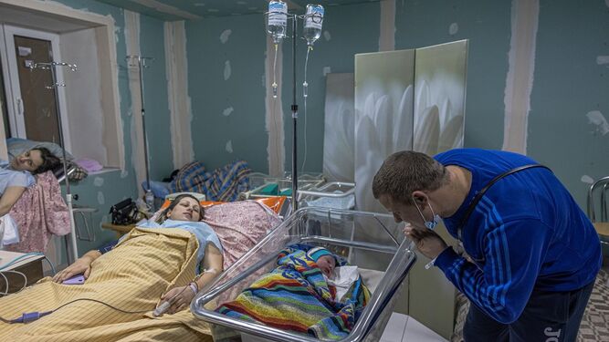 Unos padres miran a su bebé recien nacido en la maternidad de Kiev, en medio de los bombardeos rusos