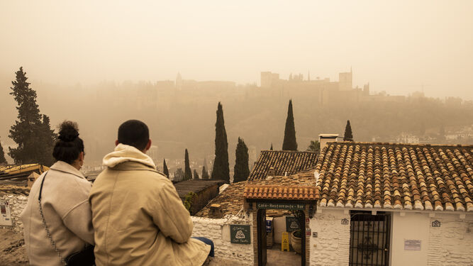 Una pareja, en el Mirador de San Nicolás, apenas puede divisar la Alhambra