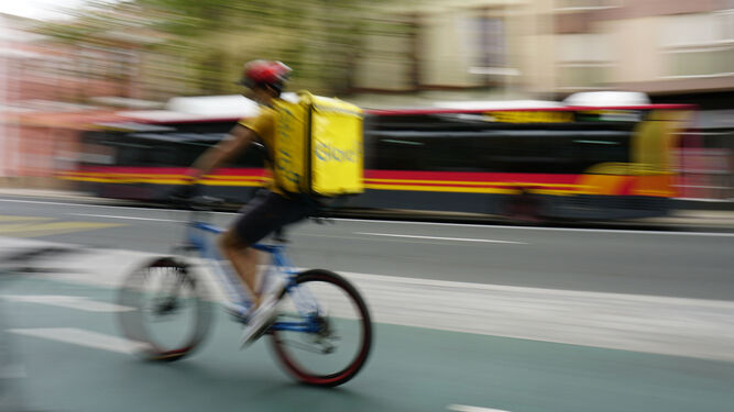 Un repartidor a domicilio circula por una antigua vía para ciclistas en Sevilla.