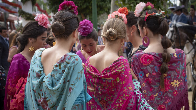 Un grupo de jóvenes con mantoncillos bordados en la Feria de Abril de Sevilla.
