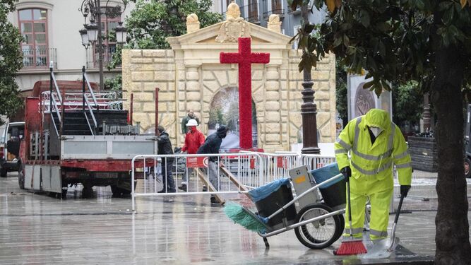 Un operario de limpieza trabaja sobre la Plaza del Carmen, mientras varias personas  desmontan una cruz.