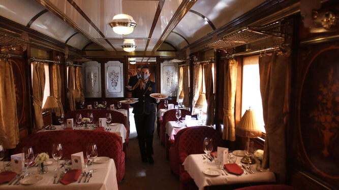 Varios camareros pasean con platos en el comedor del tren