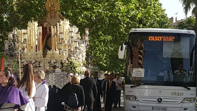Imagen del paso de un autobús junto al cortejo de la procesión de la Hermandad de La Lanzada de Granada