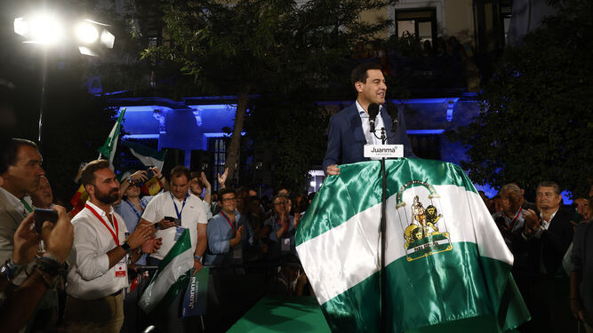 Juanma Moreno sostiene una bandera de Andalucía al finalizar el discurso de su arrolladora victoria electoral.