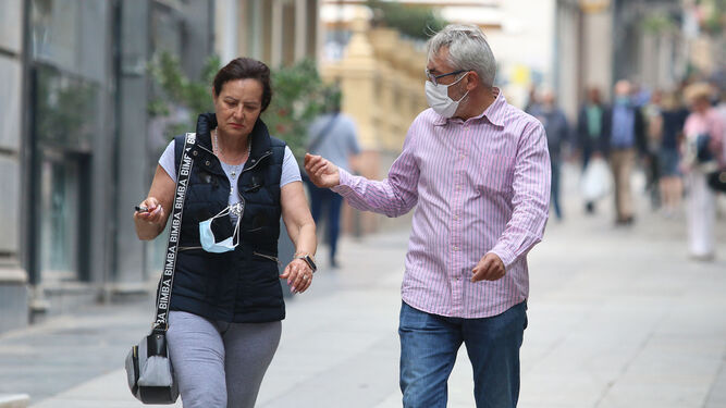Un hombre y una mujer, con y sin mascarilla, por la calle.