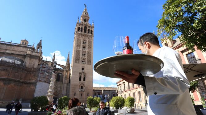 Un camarero atiende a unos clientes en la plaza Virgen de los Reyes