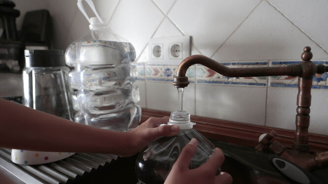 Una persona llena una botella de agua en su casa.