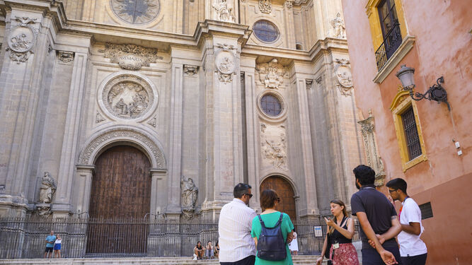 Un pequeño grupo de turistas atiende a una guía frente a la Catedral de Granada