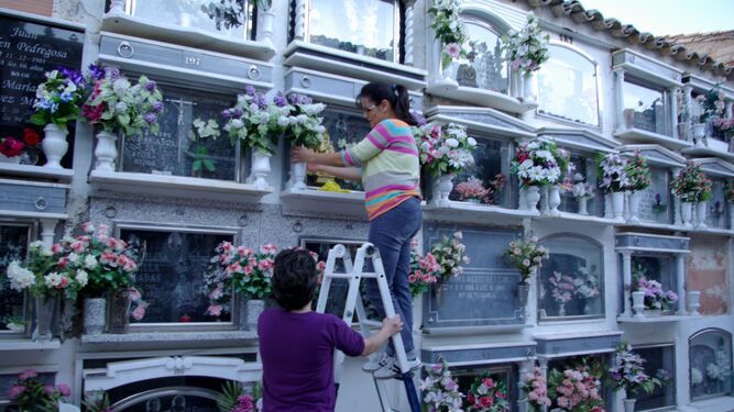 Dos mujeres colocan flores en los nichos del cementerio de Montefrío
