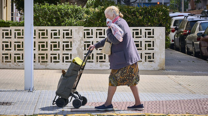 Una mujer mayor con un carrito de la compra.
