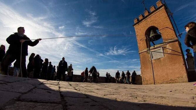 Imagen de un ciudadano tocando la campana de la Torre de la Vela de Granada