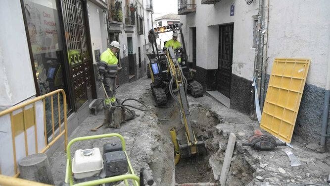 Una excavadora recoge tierra de una zanja en la calle