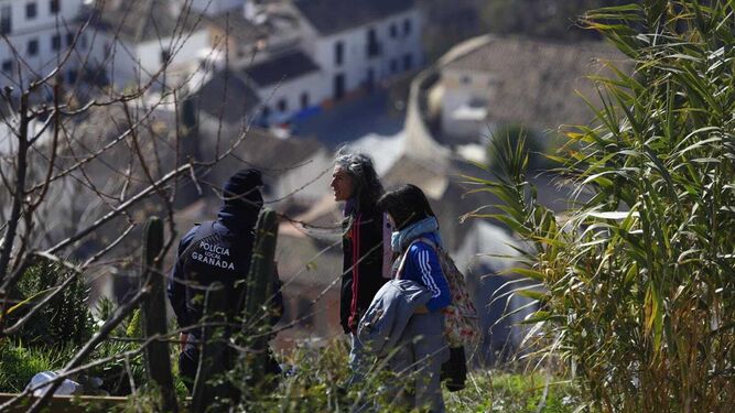 Dos vecinas de la zona pasan frente a un Policía Local en el Cerro de San Miguel