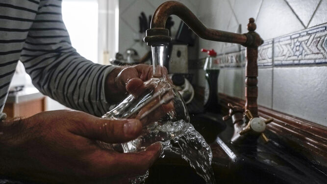 Un hombre lava un vaso en el fregadero de una vivienda.