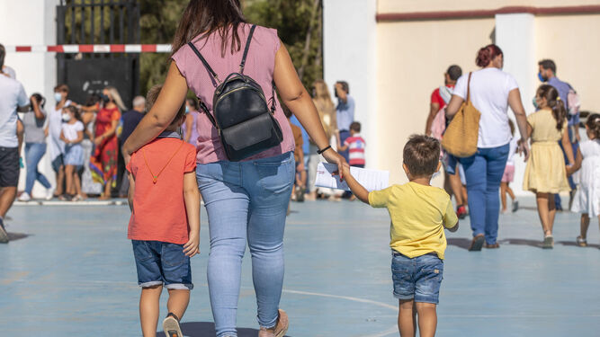Una madre junto a sus dos hijos en un primer día de colegio.