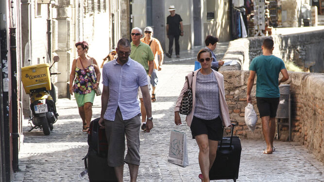 Dos personas caminan con sus maletas por la Carrera del Darro de Granada