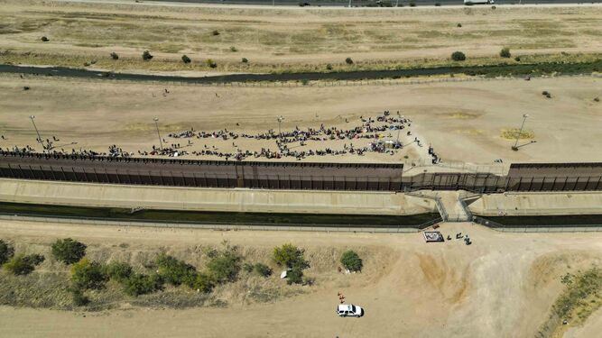 Fotografía aérea que muestra a cientos de migrantes que esperan documentos junto al muro fronterizo en El Paso, Texas .