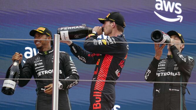 Verstappen bebe en el podio junto a Hamilton y Russell.