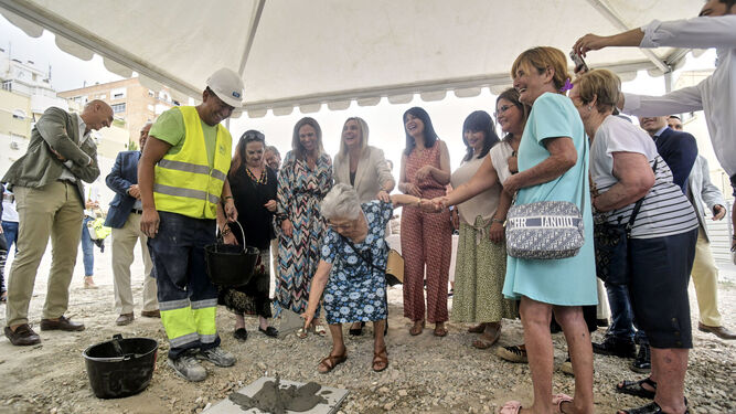 Una vecina del barrio de Santa Adela echa cemento sobre la primera piedra de la nueva construcción de viviendas en la zona