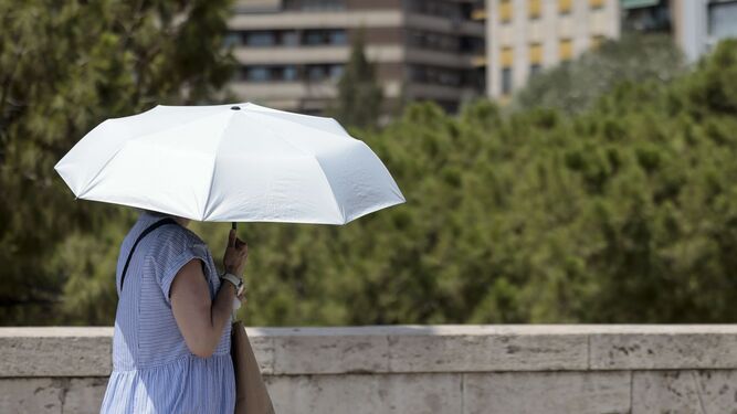 Una mujer se protege del sol con una sombrilla.