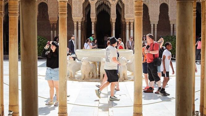 Un grupo de turistas camina por el Patioo de los leones de La Alhambra, el monumento más visitado de Granada