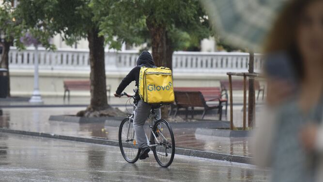 Un repartidor, en bici bajo la lluvia.