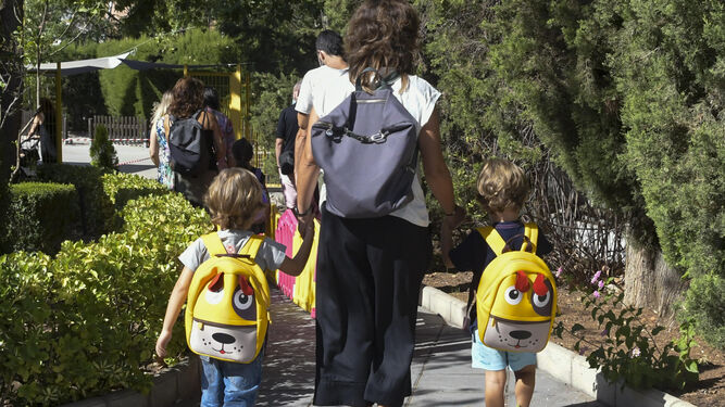 Una madre acompaña de la mano a sus dos hijos al colegio