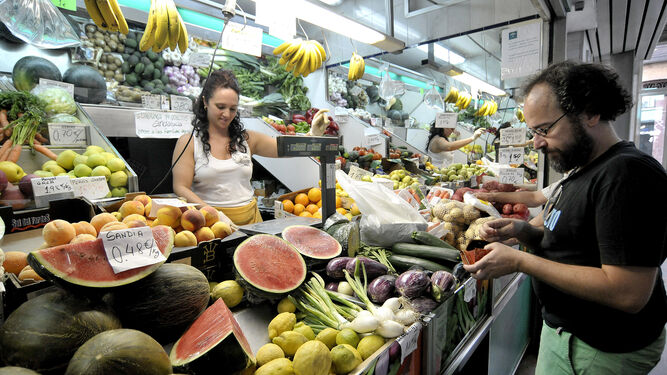 Imagen de archivo de un hombre comprando en un puesto de frutas y verduras