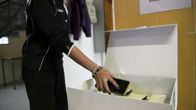 Una alumna deposita el teléfono en la caja donde se guardan los terminales al inicio de la jornada.