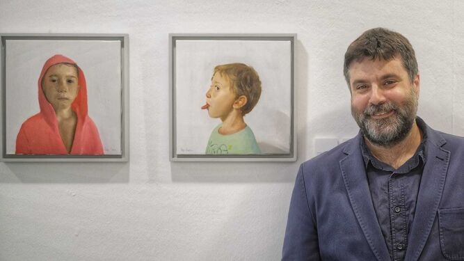 El pintor Pepe Baena posa en la Sala Rivadavia junto a los retratos de dos de sus hijos.
