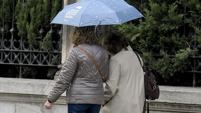 Dos mujeres se protegen de la fina lluvia de las últimas horas en Granada.