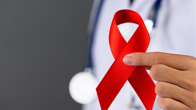 Médico sosteniendo el lazo rojo que simboliza el apoyo a la conciencia sobre el VIH.