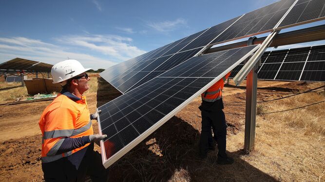 Imagen de archivo de dos operarios montando una placa solar dentro de una planta fotovoltaica