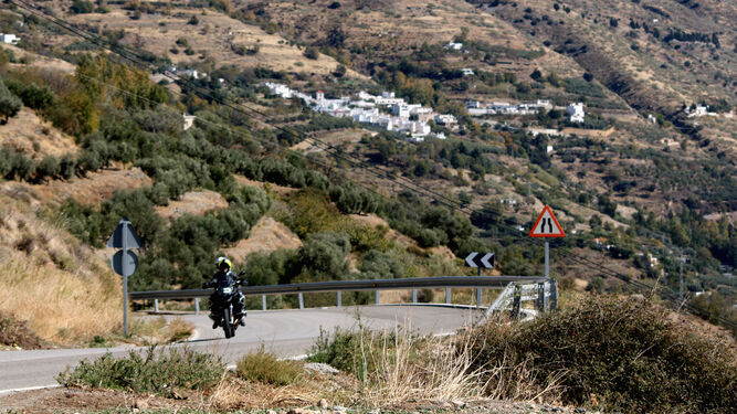 Una moto por una carretera de la Alpujarra con Soportújar de fondo