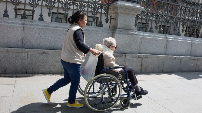 Una mujer pasea a otra en sillas de ruedas en una imagen de archivo.