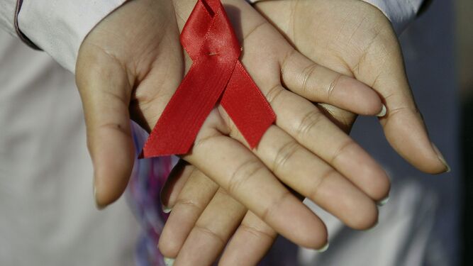 Una mujer sostiene un lazo rojo símbolo de la lucha global contra el sida.