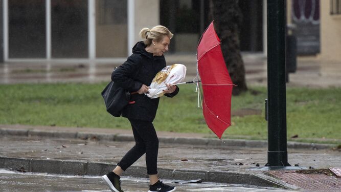 Una mujer intenta protegerse de la lluvia en Granada.