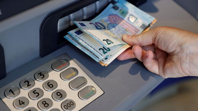Persona sacando dinero de un cajero automático | Imagen de archivo