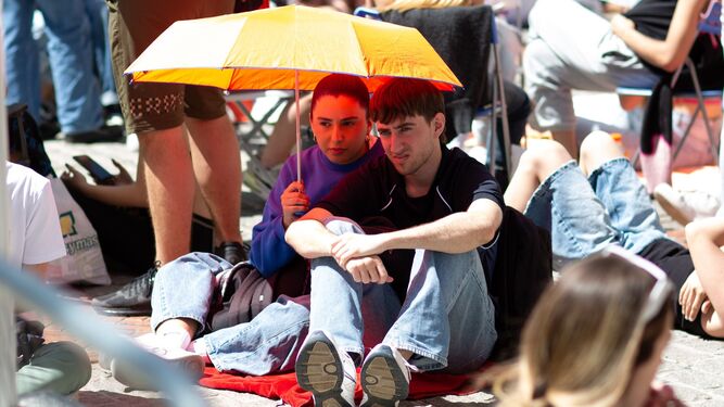 Dos jóvenes se protegen del Sol antes de entrar al concierto de Bad Gyal este sábado en Granada.